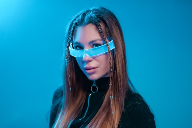 Cool cyberpunk portrait of a young woman. Woman in futuristic neon glasses.