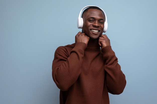 Cool energetic darkskinned american man with modern wireless headphones on the background with copy