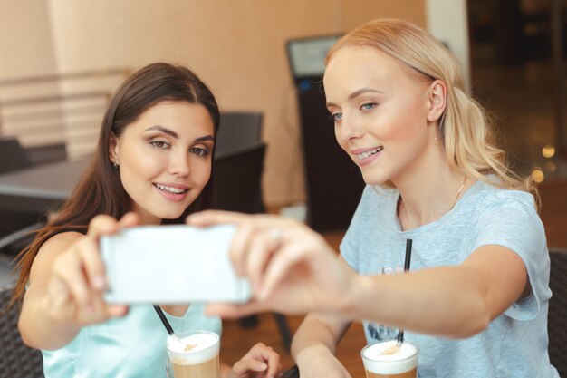 Cool fashionable girls taking a selfie in coffee shop