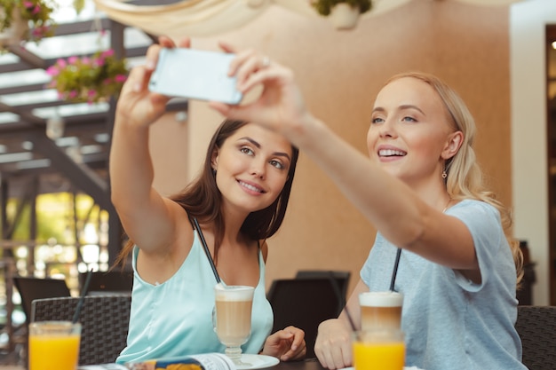 Cool fashionable girls taking a selfie in coffee shop