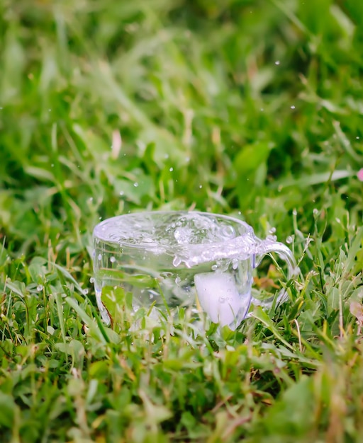 Cool fresh water with ice cubes in transparent glass cup outoors in summer day