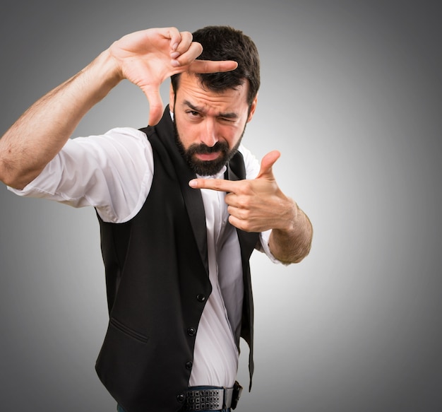 Cool man  focusing with his fingers on grey background