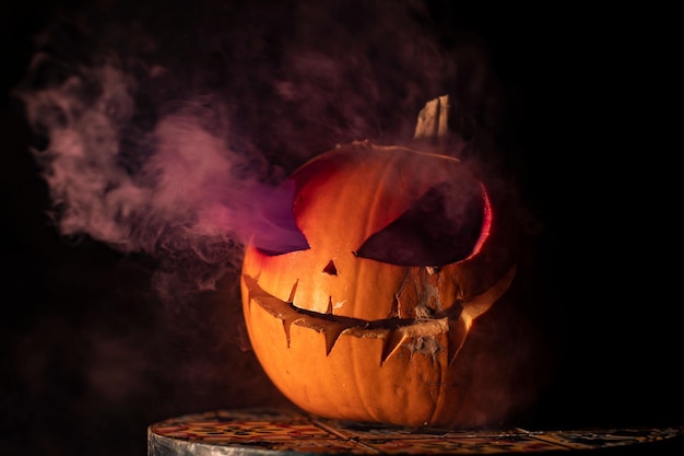 Cool shot of a Halloween carved pumpkin with purple smoke coming out of it