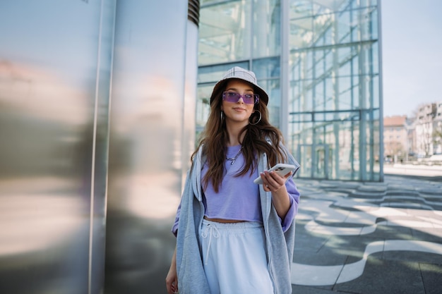 Cool young girl looking to camera and holding mobile phone high quality photo