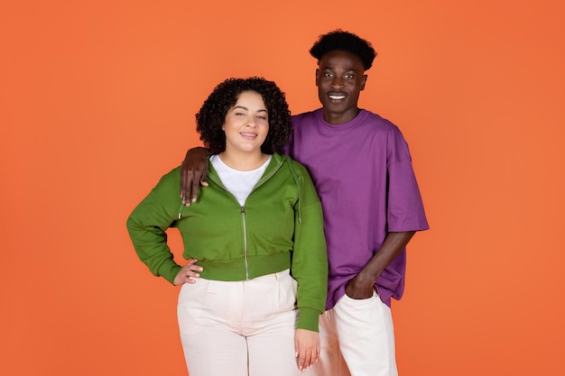 Cool young mixed race couple posing together on orange