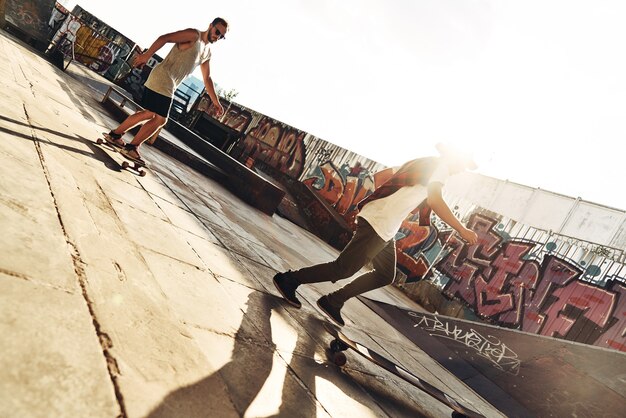 Coolest city transport. Full length of two young men skateboarding while hanging out at the skate park outdoors