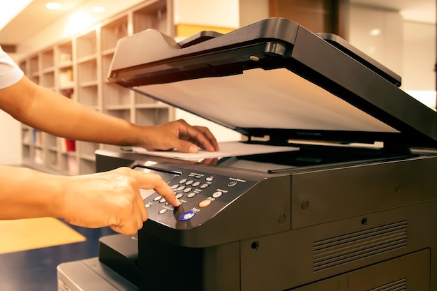 Copier printer Close up hand office man press copy button on panel to using the copier or photocopier machine for scanning document printing a sheet paper and xerox photocopy