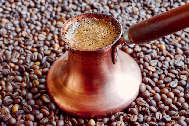 Copper cezve stands on coffee beans