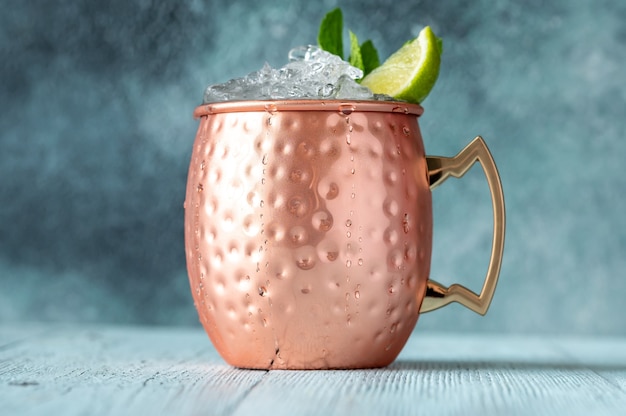 Copper mug of Moscow mule cocktail garnished with mint and lime