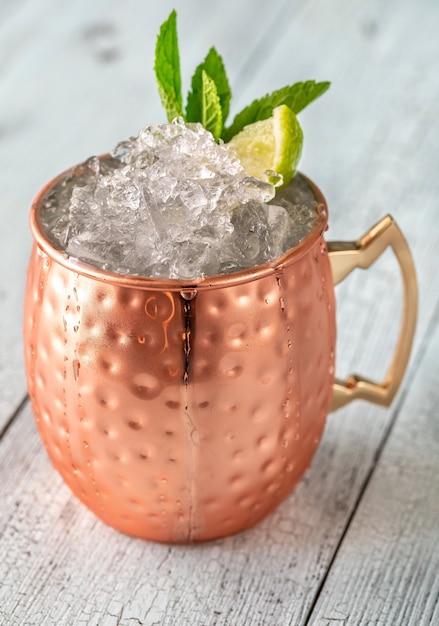 Copper mug of Moscow mule cocktail garnished with mint and lime