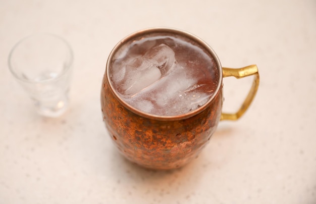 A copper mug with a drink in it and a glass of water on the side.