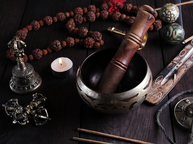 Copper singing bowl and a wooden stick on a brown table