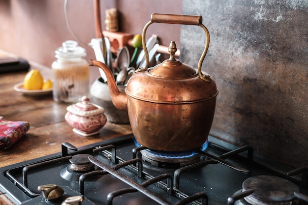 Copper vintage kettle on gas stove in modern kitchen