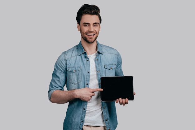 copy space on his tablet. Casual guy posing against the white wall