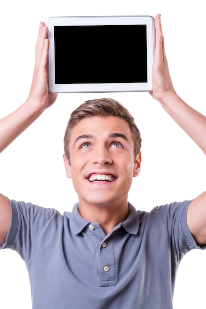 Copy space on his tablet. Happy young man holding digital tablet upon his head and smile while standing isolated on white background