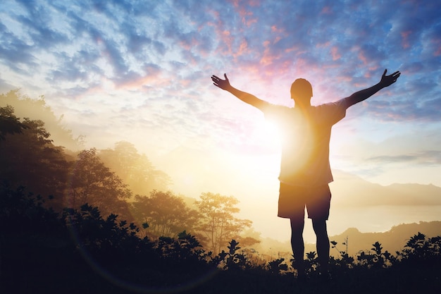 Copy space of man raise hand up on sunset sky Freedom and travel adventure concept