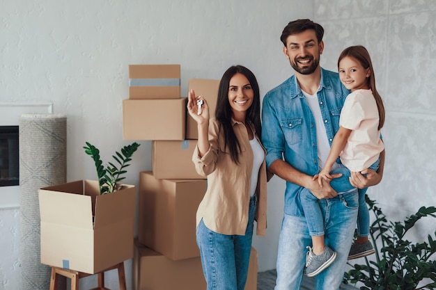 Copyspace photo of excited young couple and their cute daughter posing happily at their new appartment