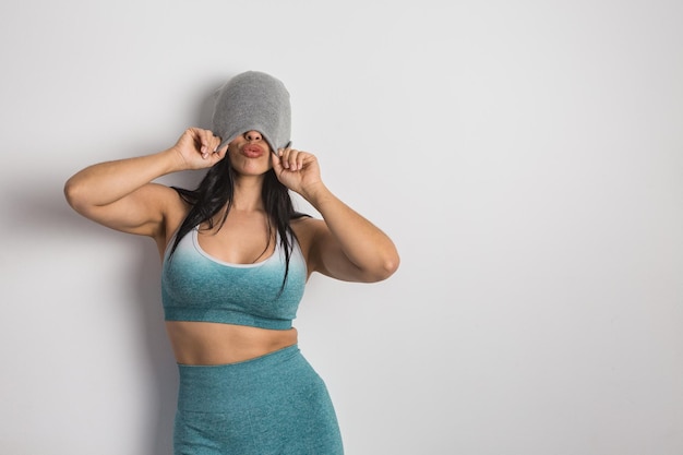 Coquettish woman covering eyes with beanie and pouting lips