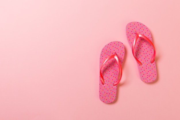 Coral flip flops on pink Background. Top view with copy space.