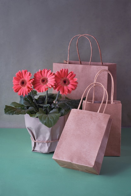 Coral gerbera daisy flowers and craft papper shopping bags on green paper 