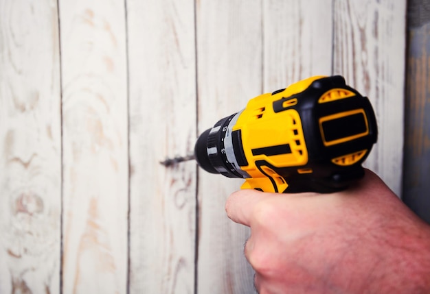 Cordless drill and a drill on a wooden background