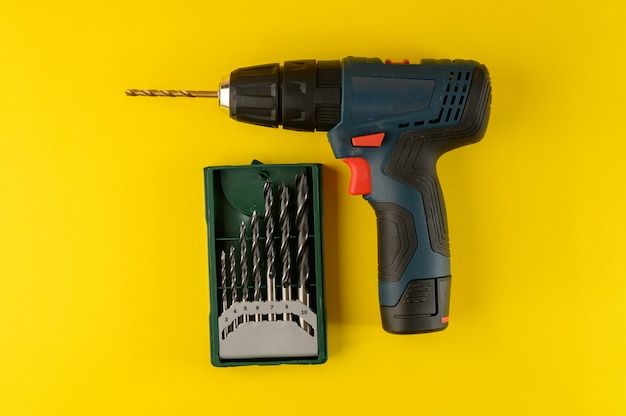 Cordless drill with drill bits isolated on yellow