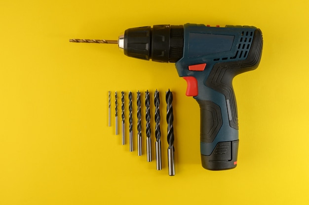 Cordless drill with drill bits isolated on yellow