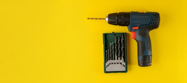 Cordless drill with drill bits isolated on yellow