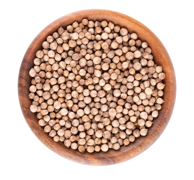 Coriander seeds in wooden bowl isolated on white background Cilantro grain Organic spice Top view