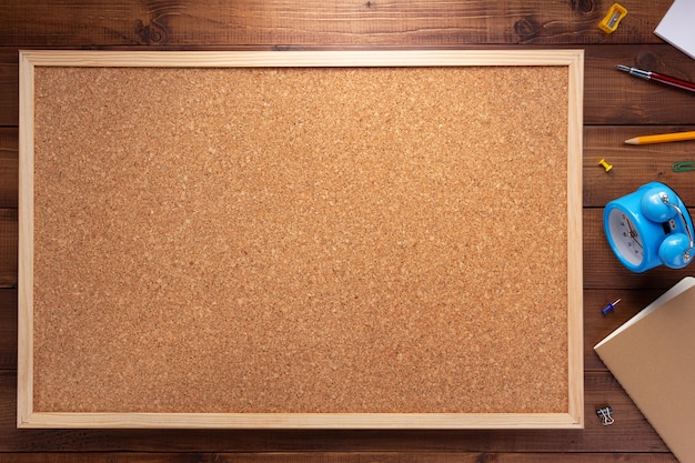 Cork board and stationery supplies on wooden table background texture