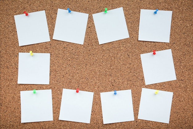 cork board with white empty notes of paper