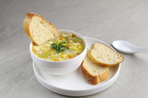 Corn and asparagus with egg drop soup in white bowl and crispy bread