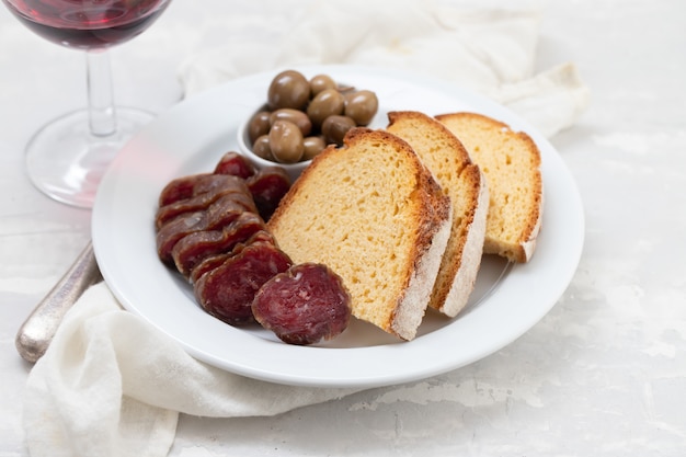 Corn bread with smoked sausage and olives on white plate