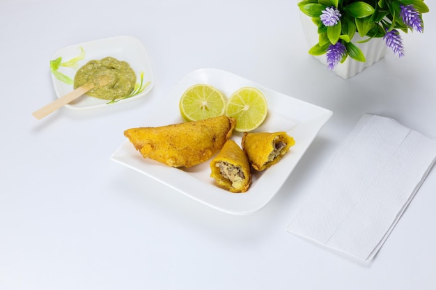 Corn empanada typical Colombian food with spicy sauce and lemon