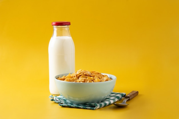 Corn flakes in a blue bowl and bottle with milk 