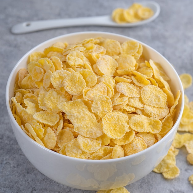 Corn flakes bowl sweeties with milk on gray cement background, close up