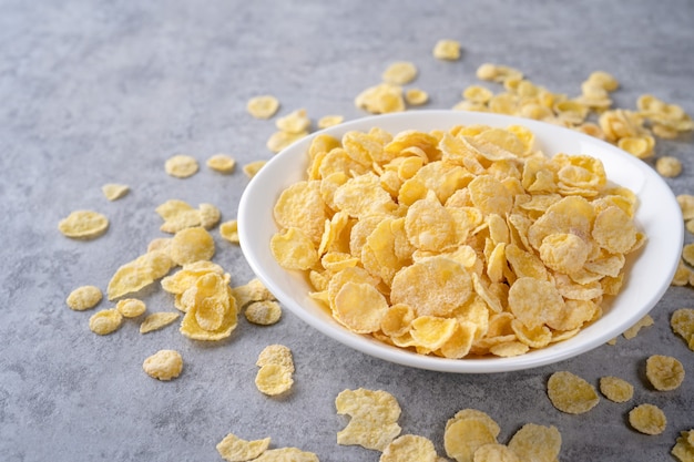 Corn flakes bowl sweeties with milk on gray cement surface, close up, fresh and healthy breakfast design concept.