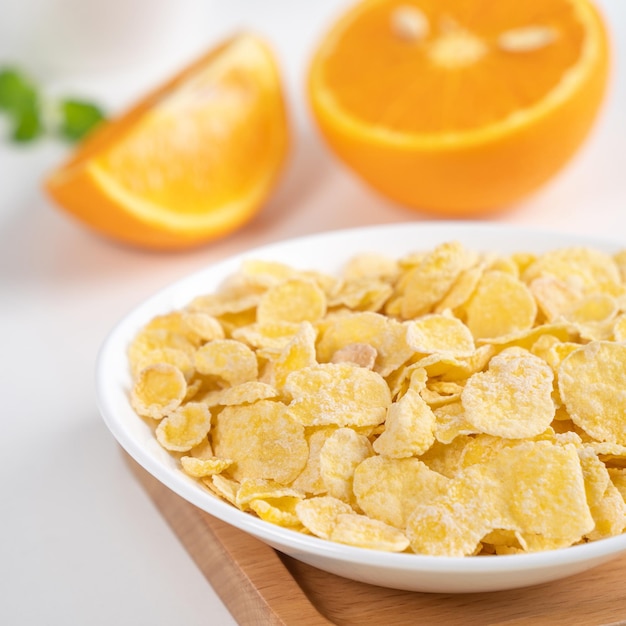 Corn flakes bowl sweeties with milk and orange on white background close up fresh and healthy breakfast design concept