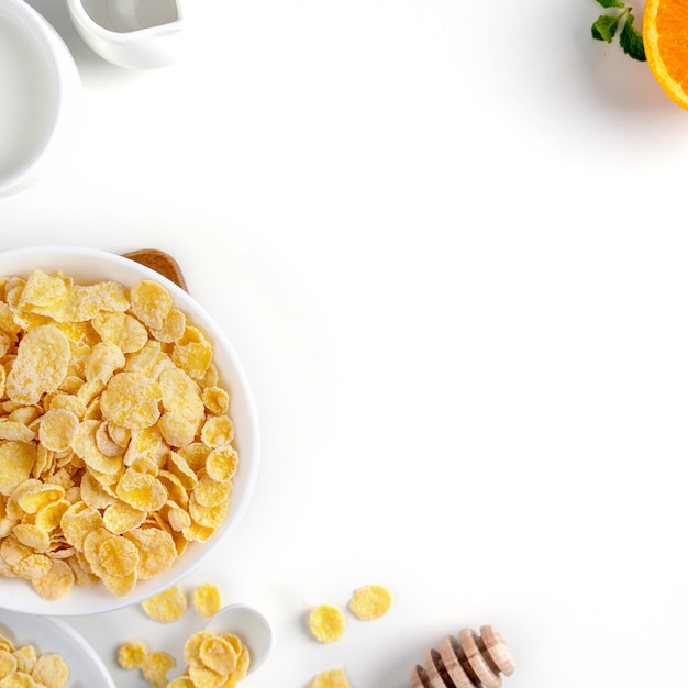 Corn flakes bowl sweeties with milk and orange on white background top view flat lay overhead layout fresh and healthy breakfast design concept