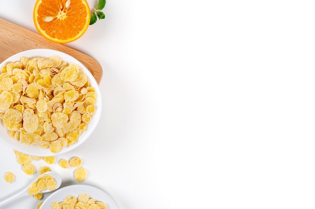 Corn flakes bowl sweeties with milk and orange on white background, top view, flat lay overhead layout, fresh and healthy breakfast design concept.