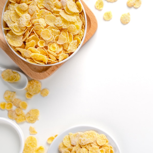 Corn flakes bowl sweeties with milk and orange on white background, top view, flat lay overhead layout, fresh and healthy breakfast design concept.