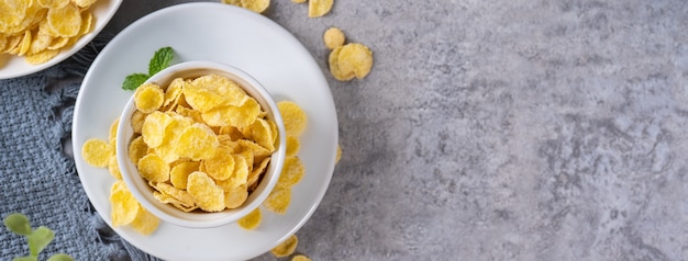 Corn flakes bowl sweets on gray cement background, top view flat lay layout design, fresh and healthy breakfast concept.