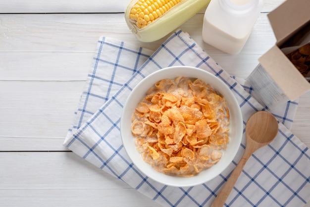 Corn flakes in bowl with milk and cereal corn flakes box, energy health, breakfast daily food. Top view with Copy space.