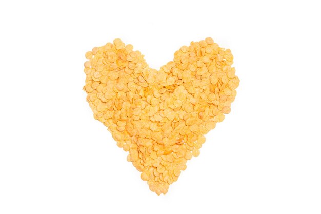 Corn flakes in heart shape on a white background with copy space