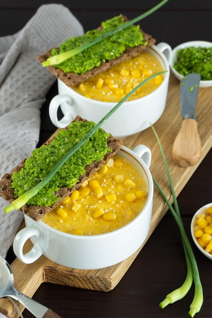 Corn soup with fresh garlic pate in bowl Healthy food on black wooden background Vegan cuisine