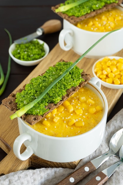 Corn soup with fresh garlic pate in white bowl Healthy food on wooden background Vegan cuisine