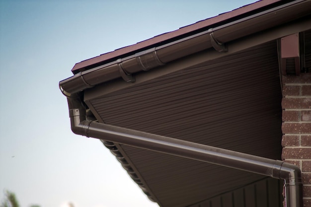 Corner of the house with new gray metal tile roof and rain gutter Metallic Guttering System Guttering and Drainage Pipe Exterior