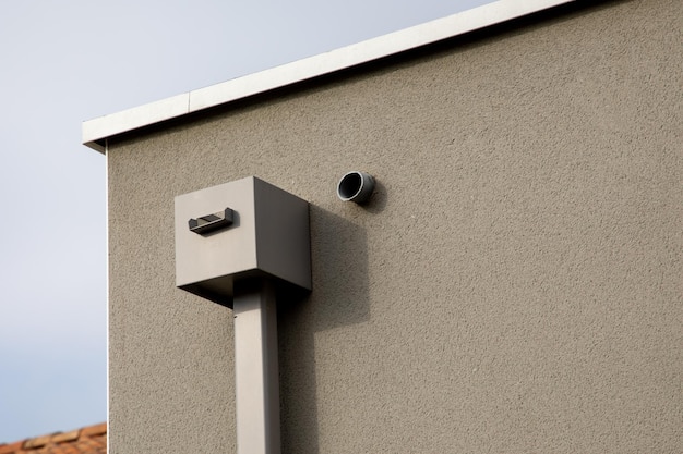 Corner new house with flat roof with modern cube gray gutter pipe