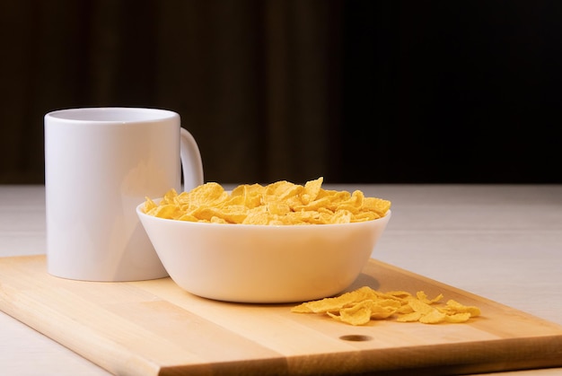 Cornflake cereals in a bowl with milk on light background, quick breakfast