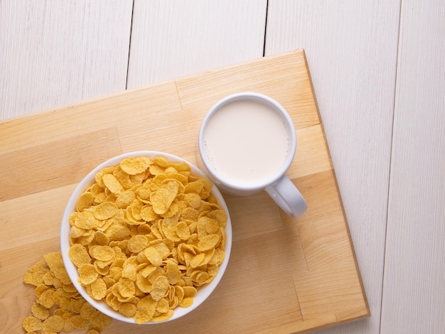 Cornflake cereals in a bowl with milk on light background, quick breakfast